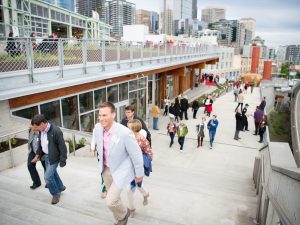 Smiling people walk up the steps of the near overlook walk path that connects Pike Place Market with the waterfront