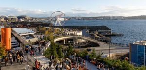 A view of Overlook Walk and the Great Seattle Wheel on a sunny day, full of people