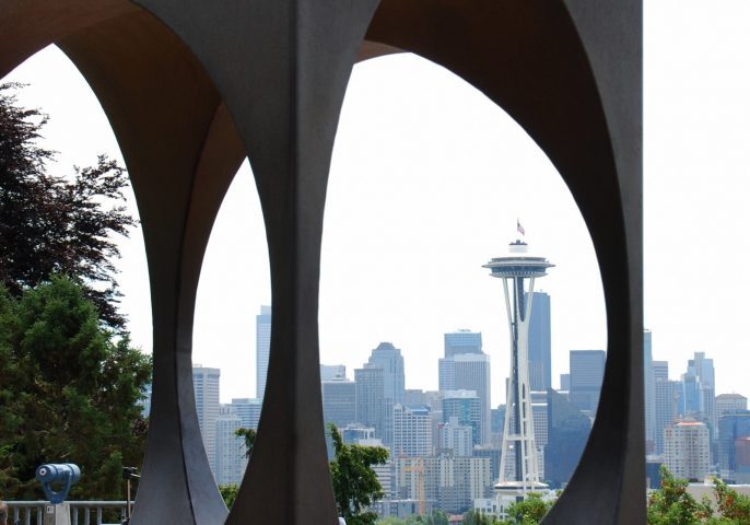 A striking metal sculpture with circular cutouts frames a captivating view of the Seattle Space Needle and skyline, celebrating the city's iconic architecture. A tribute to the creativity supported by the Seattle Architecture Foundation.
