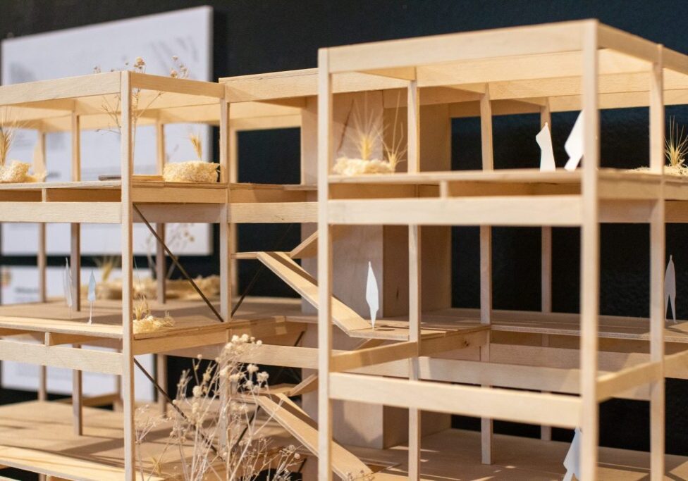Wooden architectural model of a multi-story building with open sides, featuring miniature plants and abstract interior elements, inspired by the innovative spirit of the Seattle Architecture Foundation.
